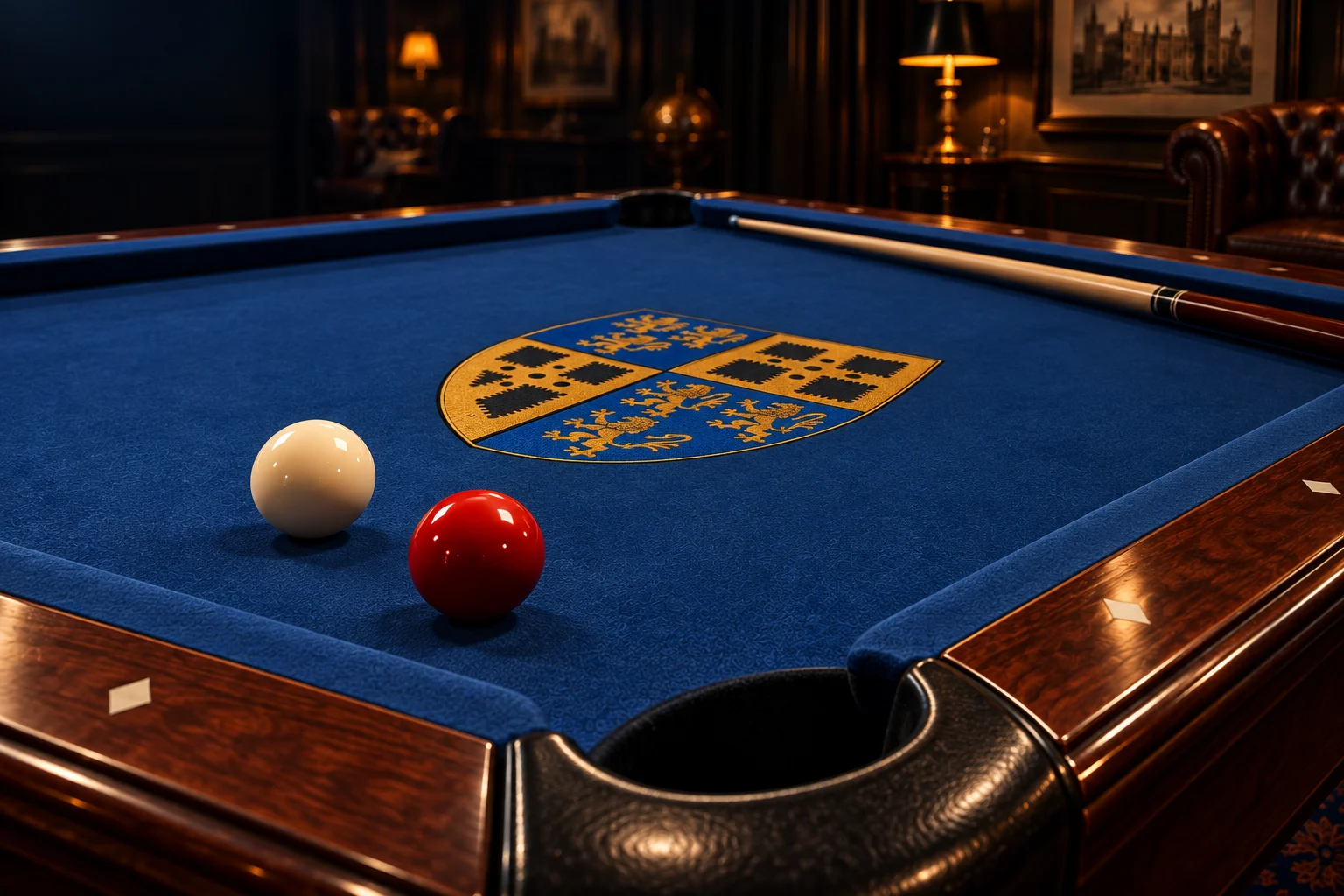 A polished red ball and ivory cue ball on blue felt, with the gold Saybrook crest and a walnut pocket rail.